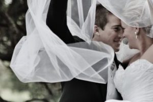 pretty bride and groom under a veil looking at each other with love